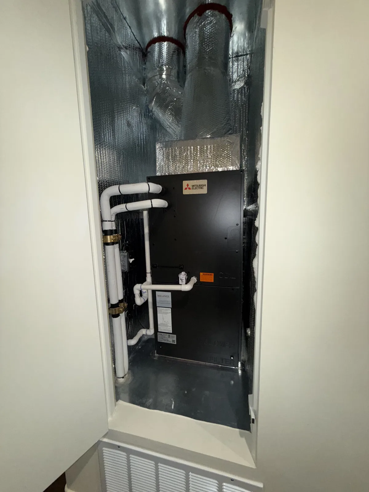 Mitsubishi air handler custom-fitted inside a hallway closet with insulated ductwork