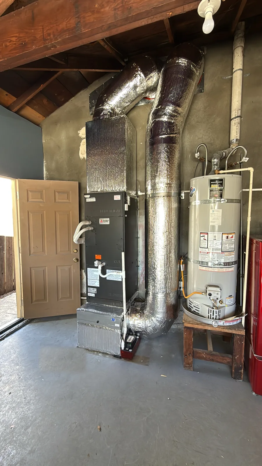 Garage heat pump air handler with custom-wrapped ductwork beside a water heater